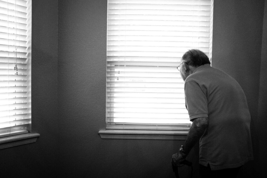 Elderly man looking through the window