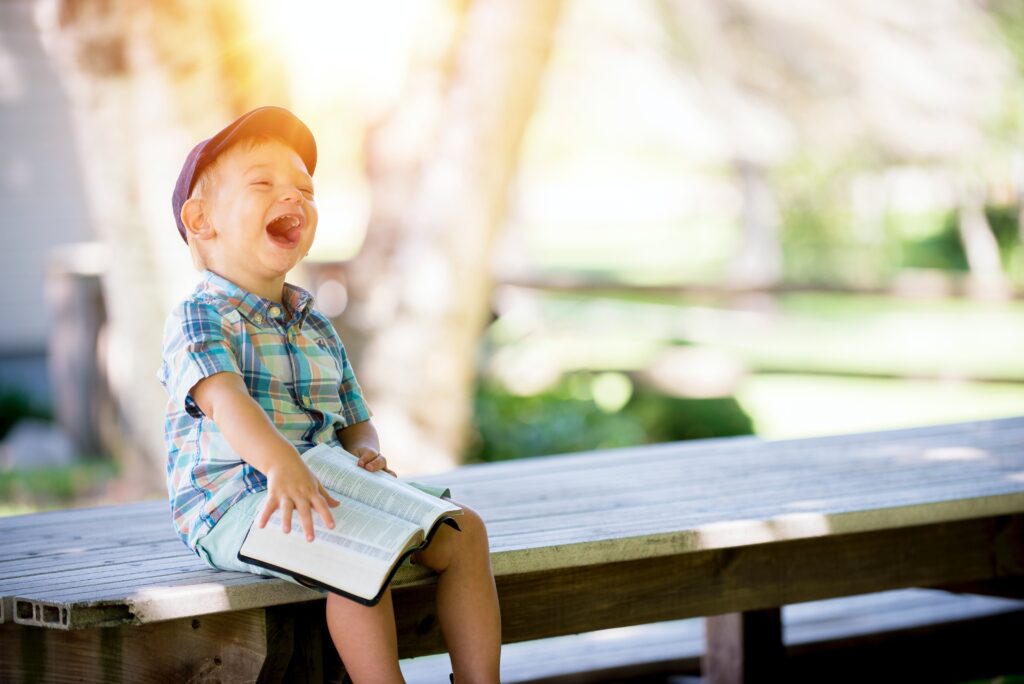 Little boy with a book laughing