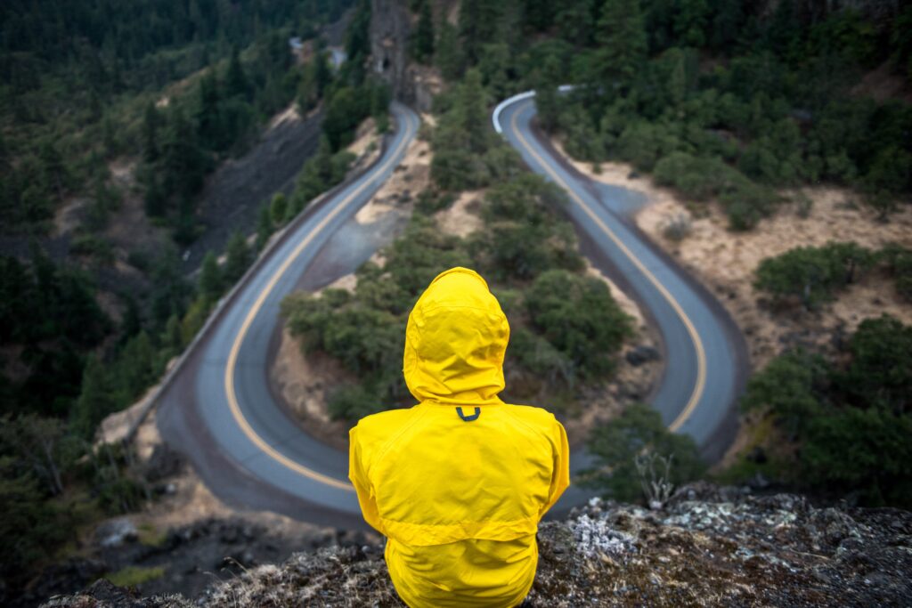 Person wearing a yellow jacket sitting on a cliff