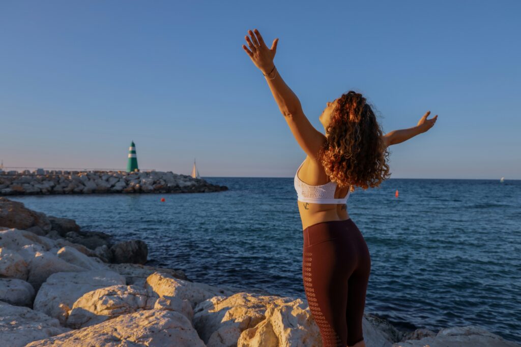 Woman by the seashore with hands up