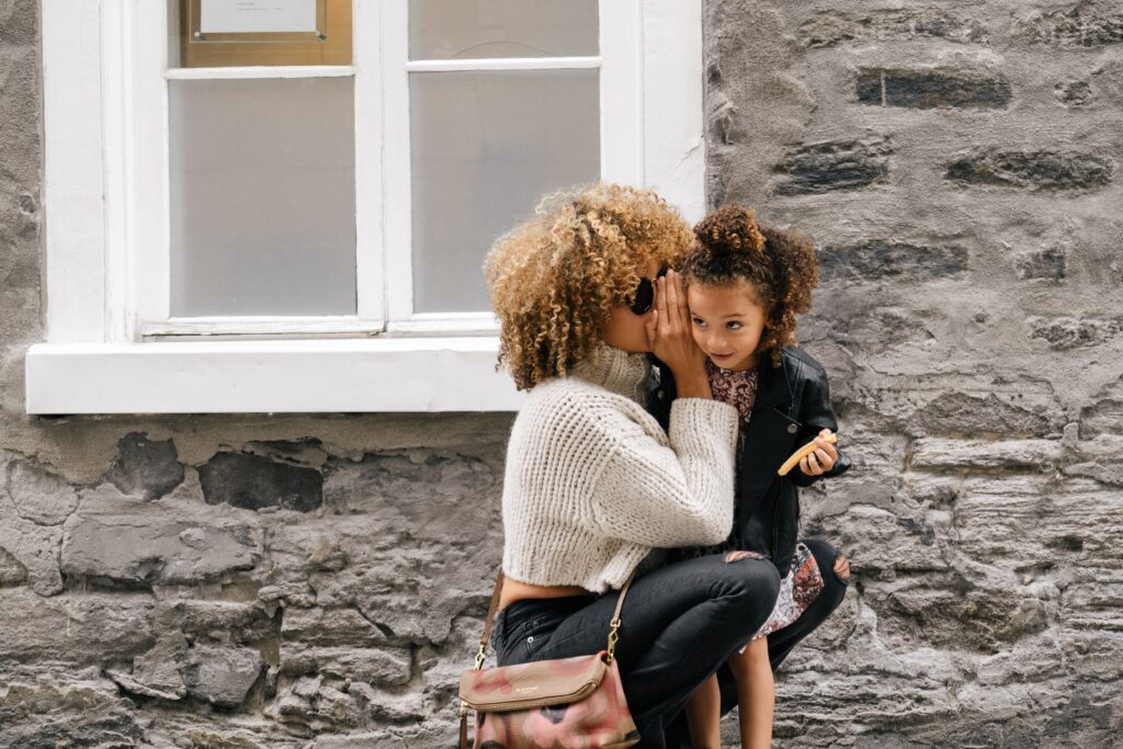 Mother whispering into daughters ears